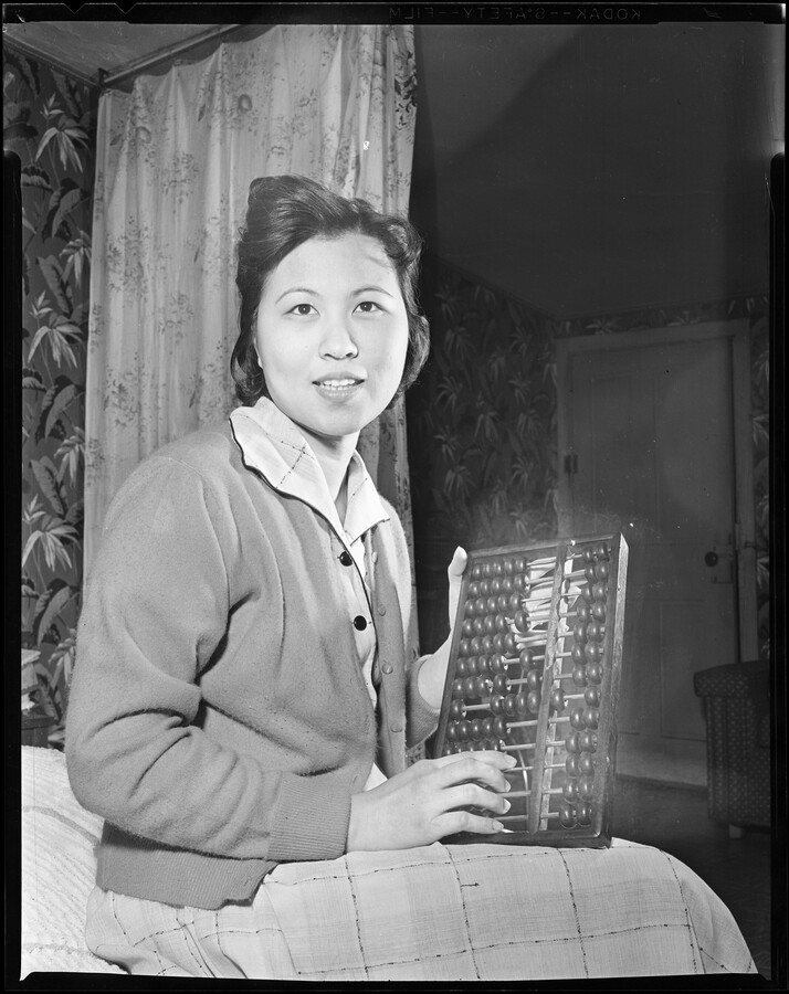Portrait of Tuey M. Hom seated with an abacus. Born Tuey May Kung, Hom was the daughter of Henry Kung and his wife Wong Shee Kung. She was born, raised and educated in Guangdong, China, and married James K. S. Hom in 1949; eight years later the couple emigrated to Baltimore, Maryland. Mrs. Hom’s husband…