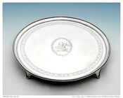 Circular footed serving tray decorated with two rows of scalloped border and an interior decorative etched band. The tray features a central motif of a mother dragon with babies surrounded by a circular vine border.