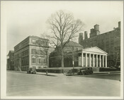View of buildings on the University of Maryland, Baltimore campus at the corner of Green and Lombard Streets in Baltimore, Maryland, along with two parked cars. On the left is the School of Dentistry at 37-51 South Greene Street, known then as The Baltimore College of Dental Surgery (BCDS). In the center is Davidge Hall…