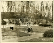 Visitors at the Baltimore Zoo (now the Maryland Zoo in Batimore) located in Druid Hill Park in northwest Baltimore City, Maryland. A bear can be seen in the enclosure on the left. The zoo, one of the oldest in the United States, opened in 1876.
