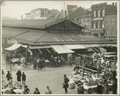Lexington Market, founded in 1782, located at 400 West Lexington Street, Baltimore, Maryland. Shows outdoor vendors and patrons. Signs in the background can be seen for Dimling's Groceteria and Great China Tea Company. A sign above the market reads "Tuesdays Fridays Saturdays."