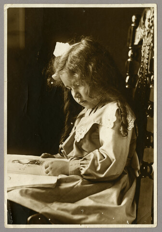 Portrait of young girl seated and reading — undated