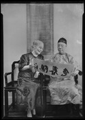 Dr. Chao-Ming Chen seated beside an unidentified woman, both examining a scroll. The woman is likely Dr. Chen's wife, Hsiu Lien Chen. Natives of Fuzhou, China, the Chens immigrated to the United States in 1920 and were longtime residents of Baltimore, Maryland. Dr. Chen was a community leader, an instructor in Chinese language and literature…