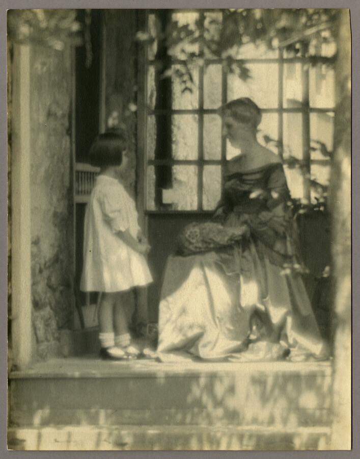 Portrait of a woman and child in front of window.