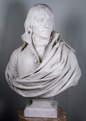 This bust of Napoleon Bonaparte I (1769-1821) shows the French leader as a younger man with long hair wearing a coat with a high collar and a sash. Napoleon I reigned as the Emperor of the French from 1804 to 1815.