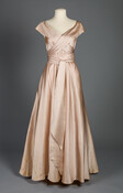 Pale pink, silk faille evening gown designed and owned by American fashion designer Claire McCardell. Its distinguishing construction detail is its lack of shape until the wearer wraps and ties the self-fabric waist sash to define the waist.